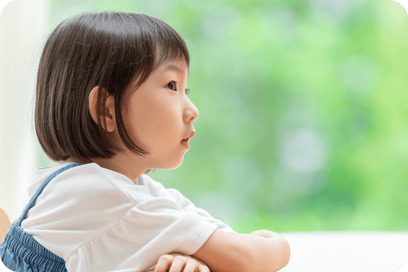 机の前で前を見つめている女の子の横顔