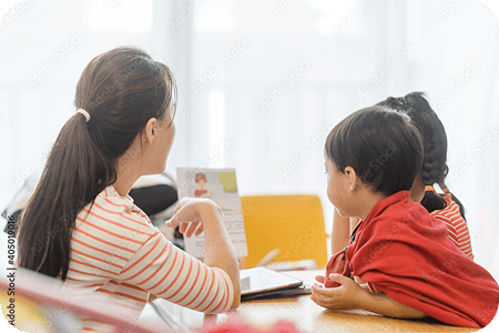 先生が示す資料を複数の子どもが見ている様子