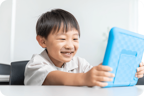 うつ伏せに寝転びながらタブレットを見ている男の子