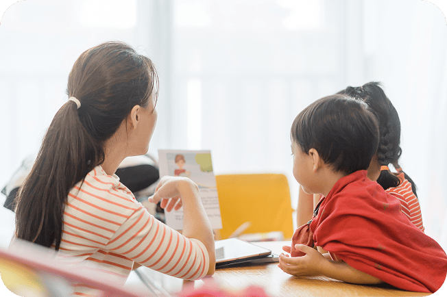 先生が示す資料を複数の子どもが見ている様子